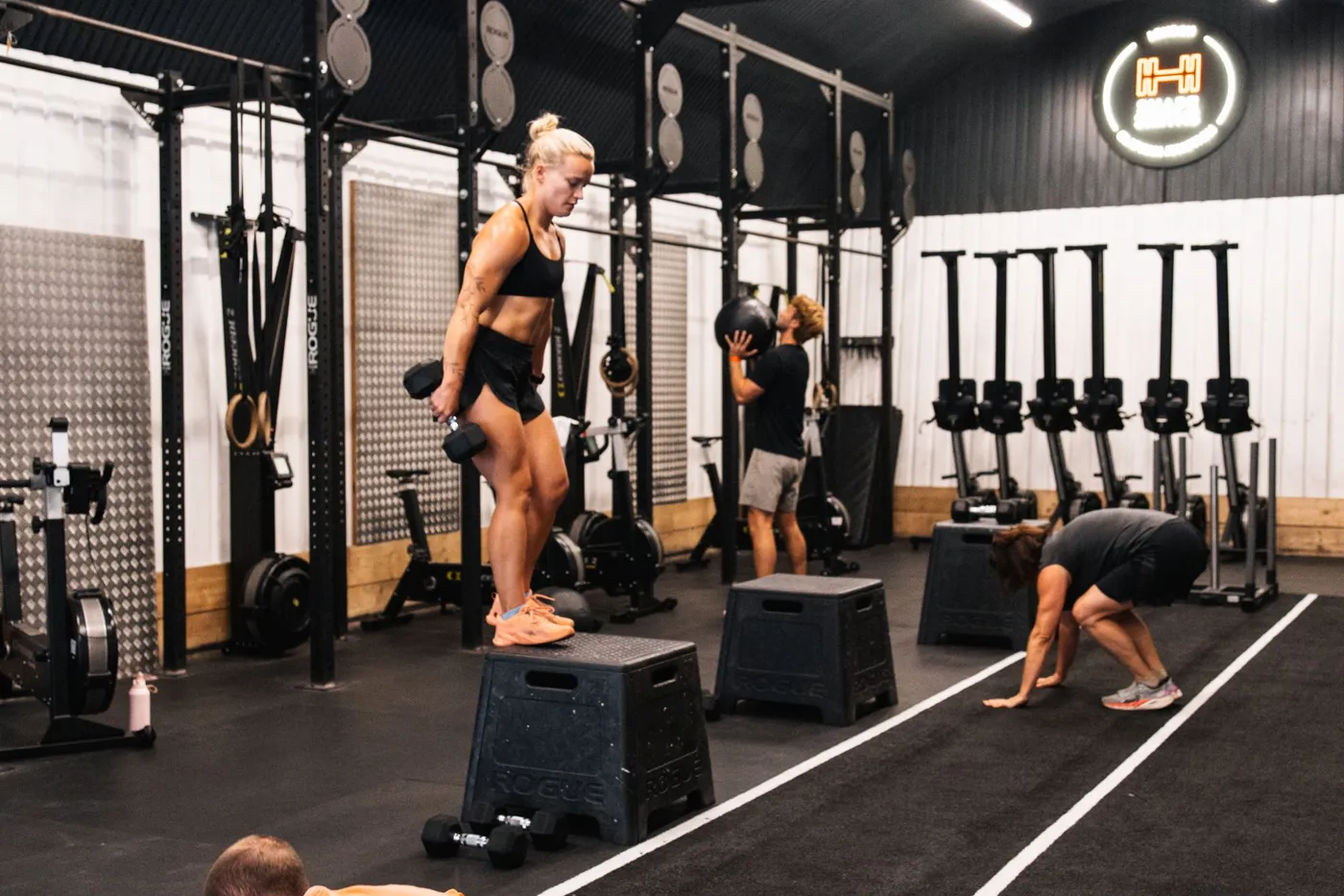 Members training on plyo boxes and with a medicine ball in an Engine class at Shapesmiths, with the rowers lined up behind